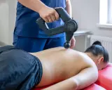 Fizjoterapeuta wykonuje masaż wibracyjny pleców. Choć zazwyczaj przynosi ulgę, warto pamiętać o potencjalnych skutkach ubocznych masażu wibracyjnego.