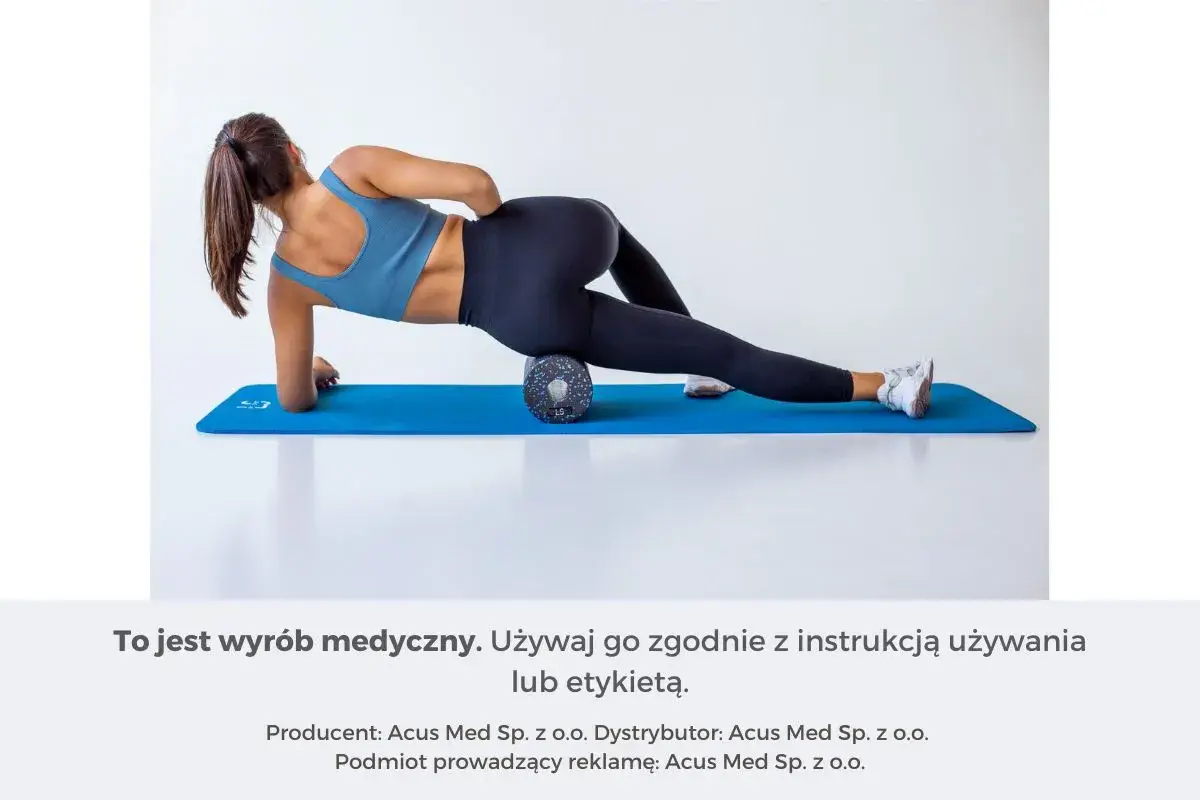 Kobieta wykonuje rolowanie mięśni uda na wałku do masażu, leżąc na macie.